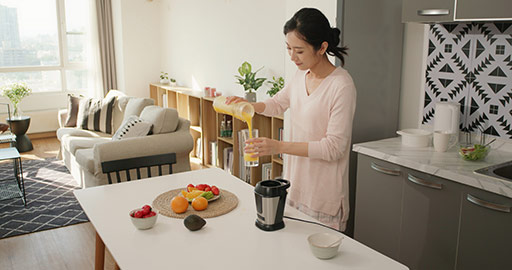 Happy young Chinese woman making juice at home,4K