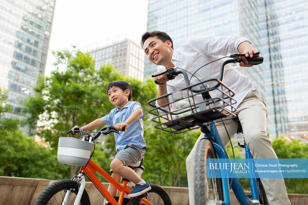 Happy young Chinese father and son riding bikes