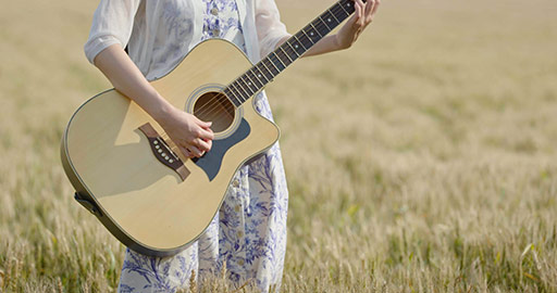 Happy young Chinese woman playing guitar in wheat field,4K