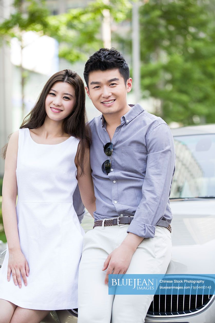 Happy young Chinese couple and car