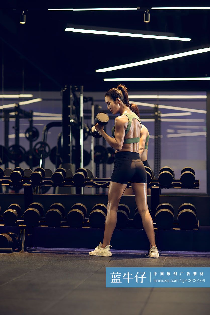 年轻女士在健身房举哑铃