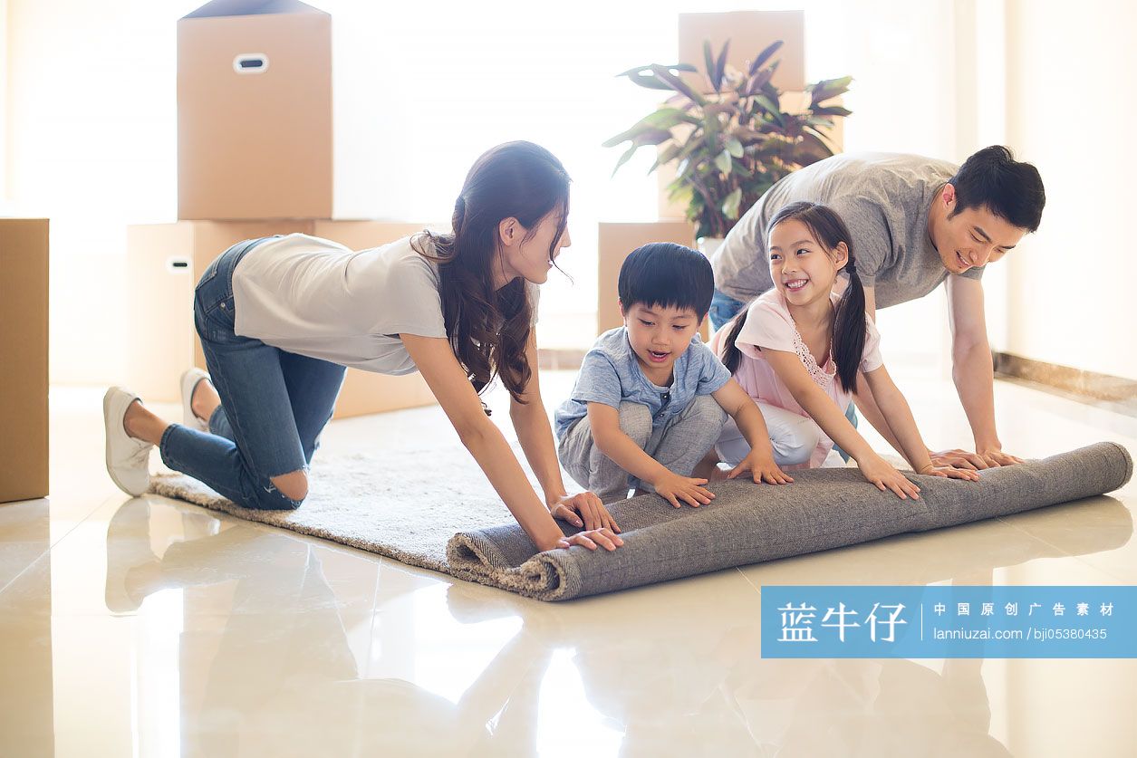 快乐的年轻家庭在新房里铺地毯