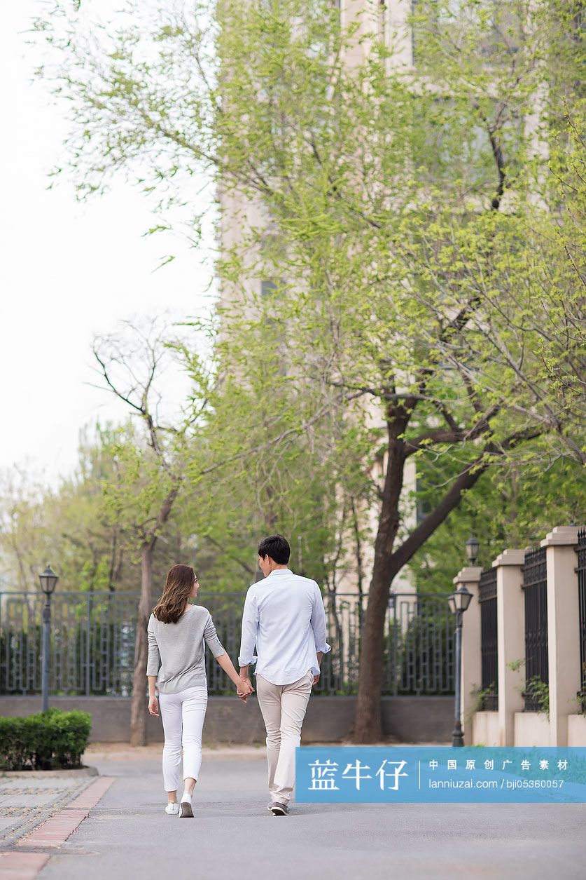 年轻情侣手牵手散步的背影