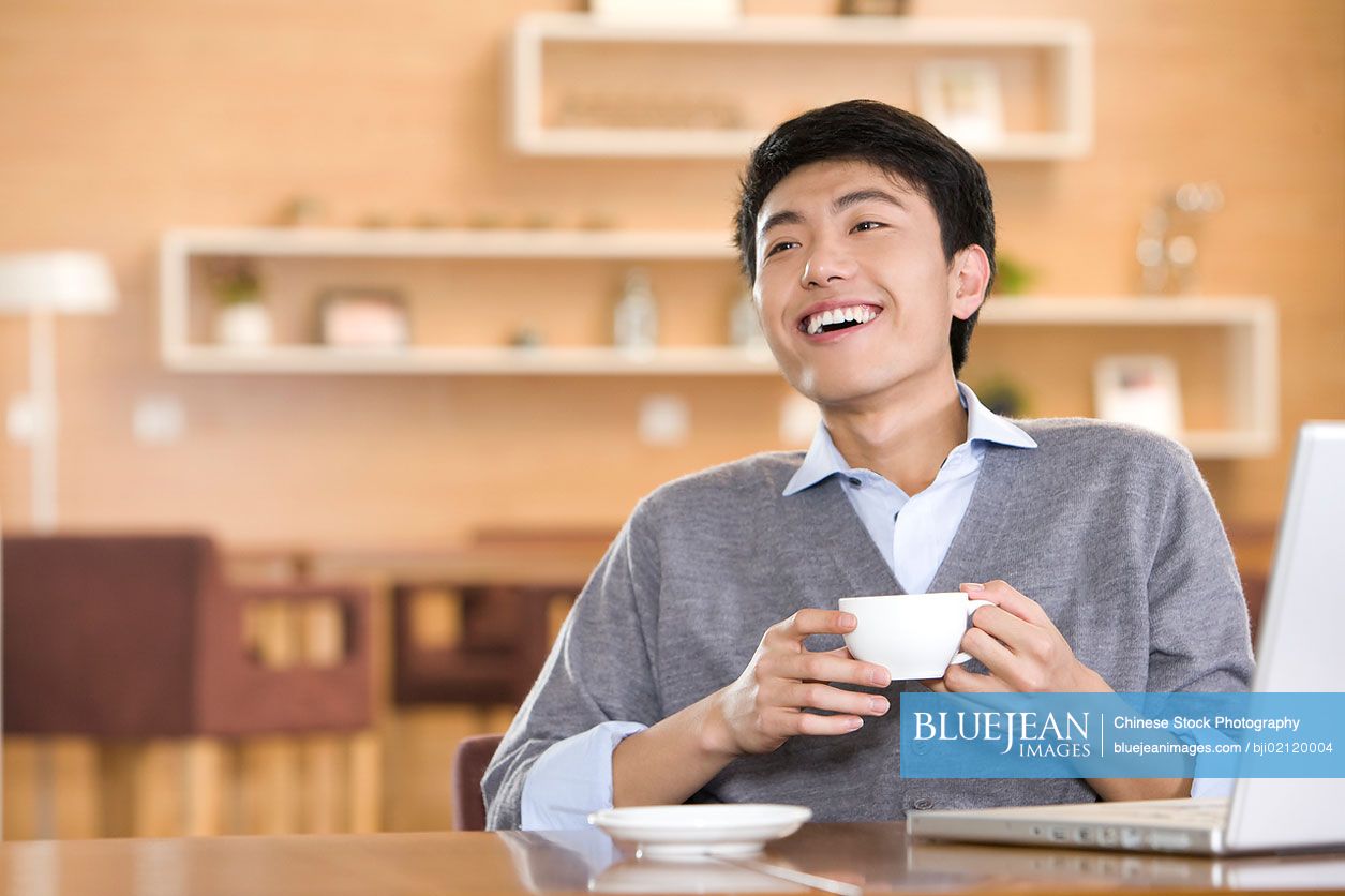 Young Chinese man using laptop at coffee shop