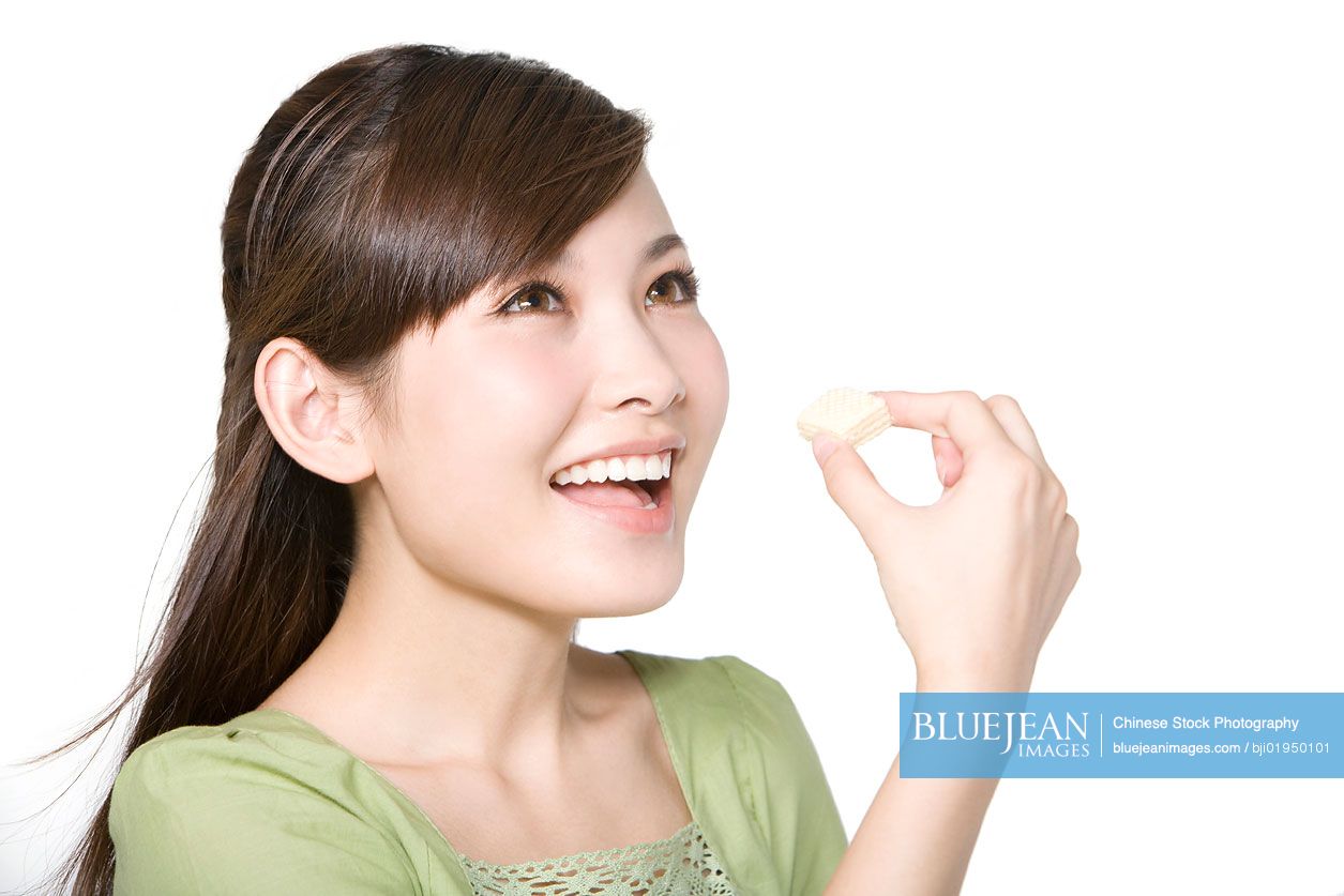 Portrait of young Chinese woman eating wafer cookie