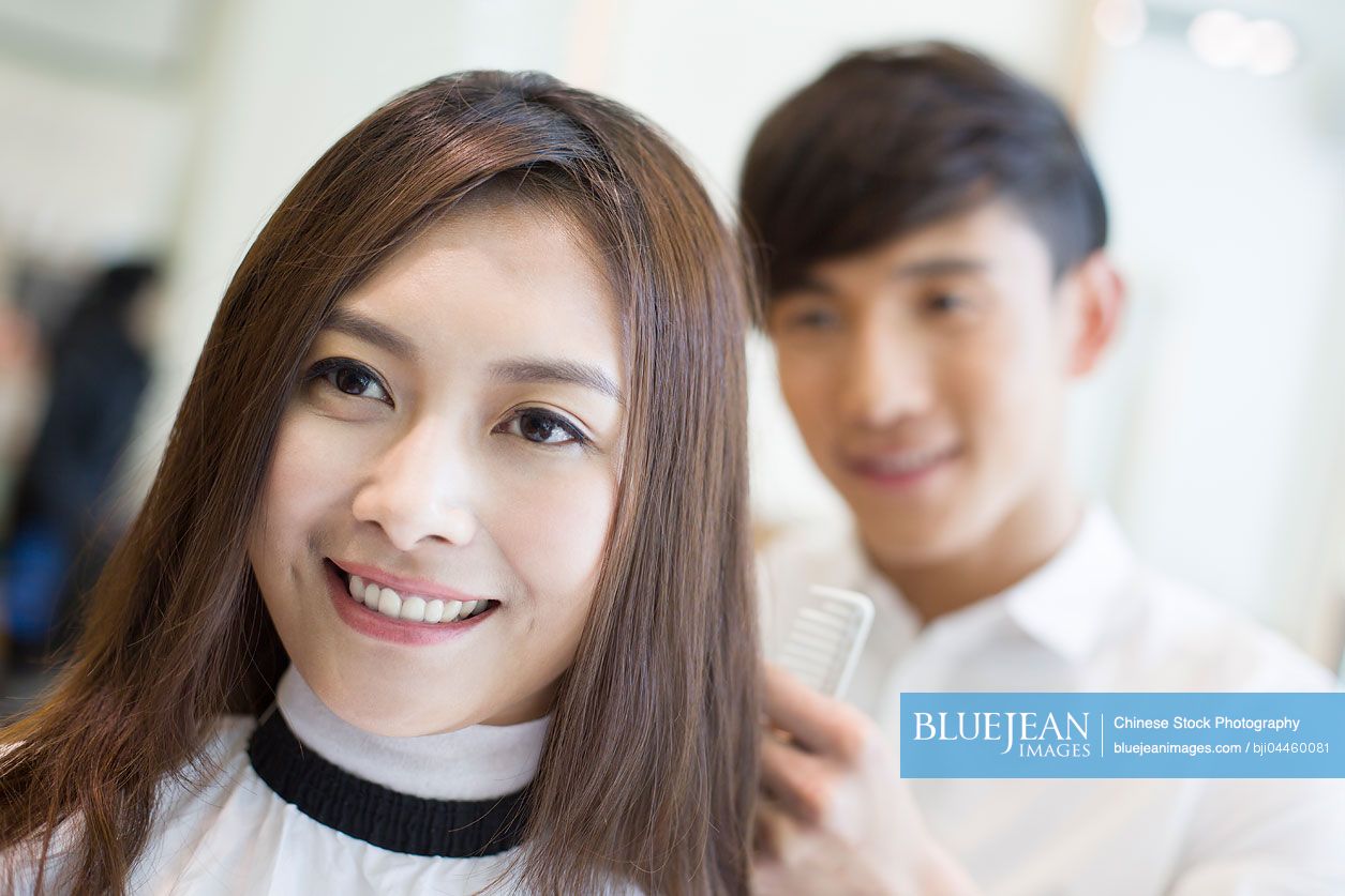 Young Chinese woman having haircut in barber shop