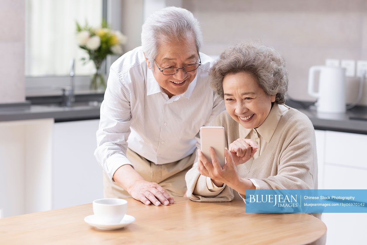 Senior Chinese couple  using smartphone at home