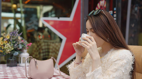 Cheerful young Chinese woman drinking coffee in café,4K