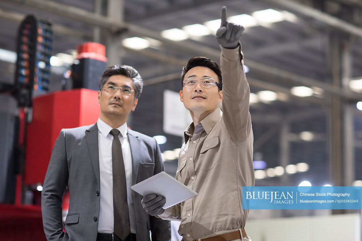 Chinese businessman and engineer talking in the factory