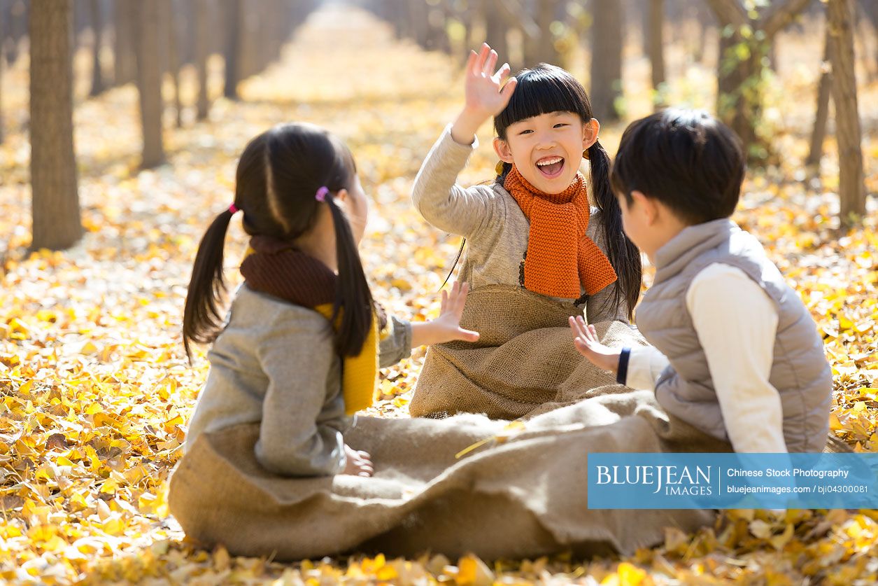 Three Chinese children playing in autumn woods