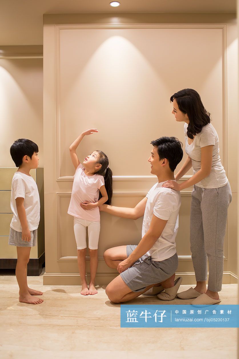 快乐的年轻父母给孩子量身高