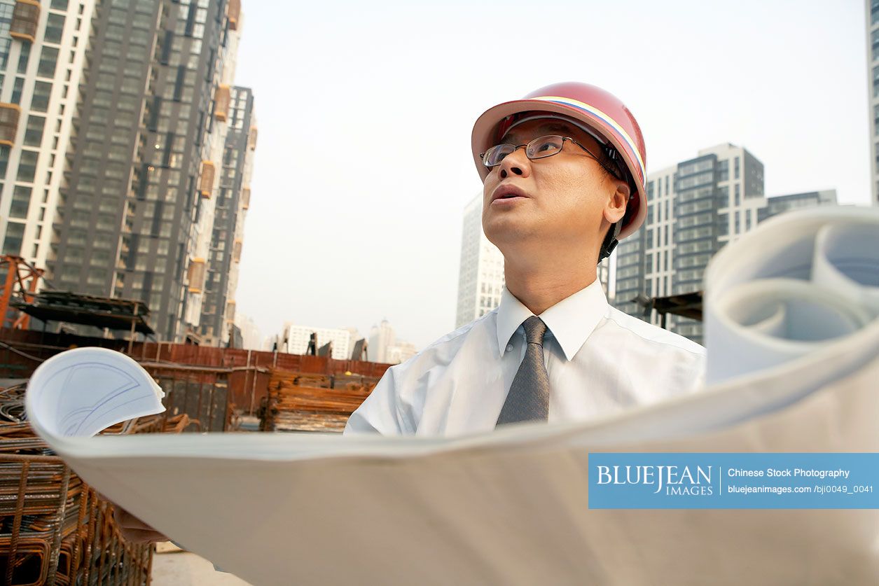 Chinese Construction Contractor Looking At Building Plans