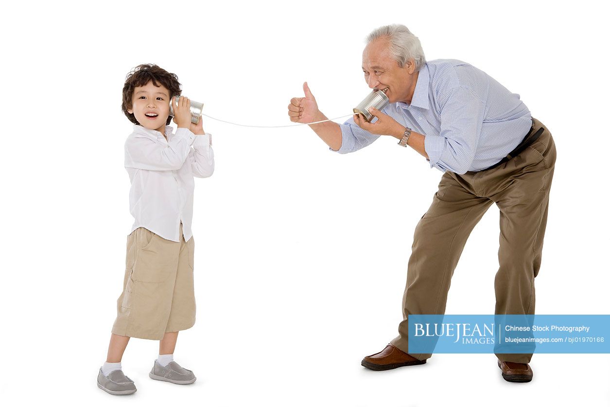 Chinese grandfather and grandson playing with a tin-phone