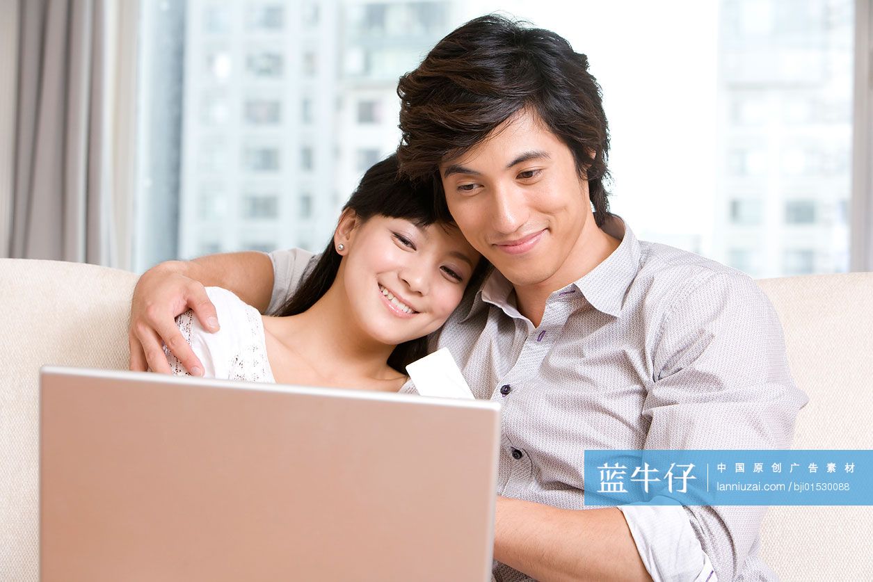 在沙发上用电脑的情侣