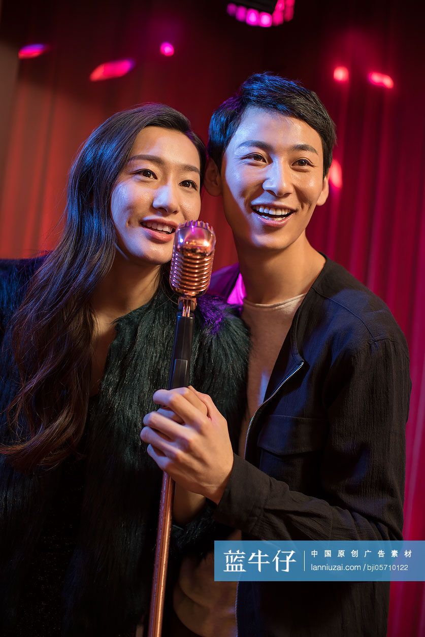 快乐的年轻情侣在KTV唱歌