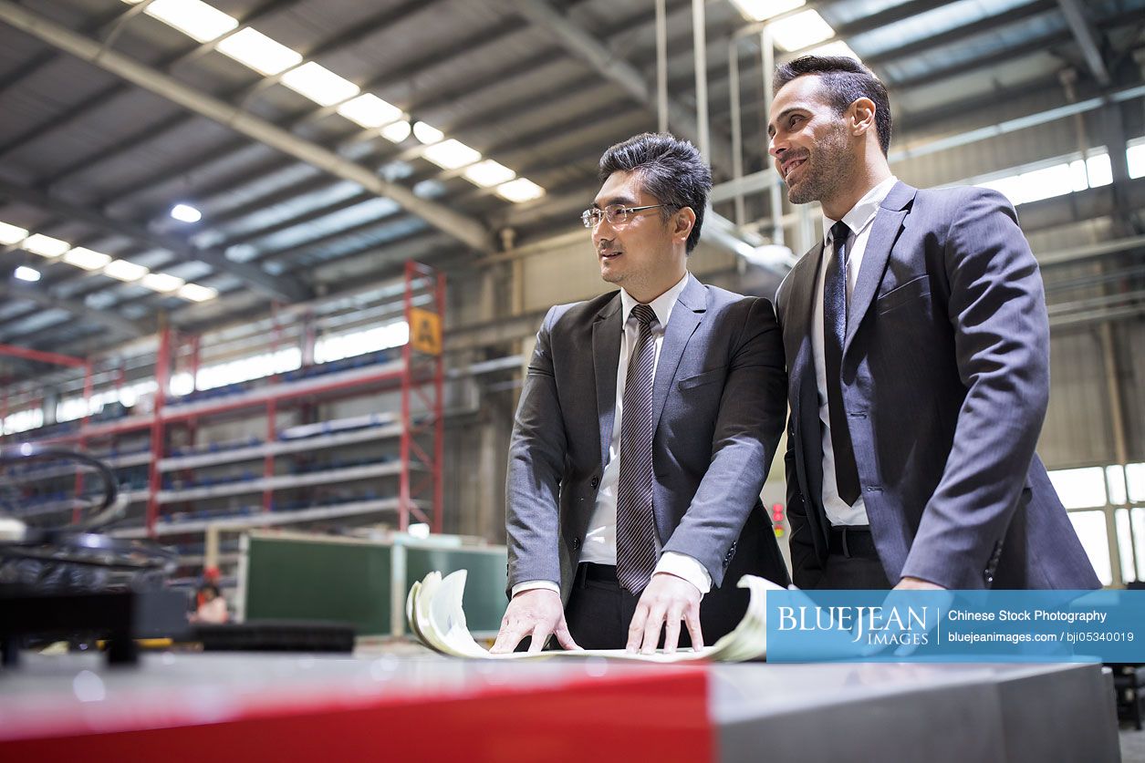 Businessman and engineer talking in the factory