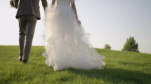 新郎和新娘在草地上牵手走路