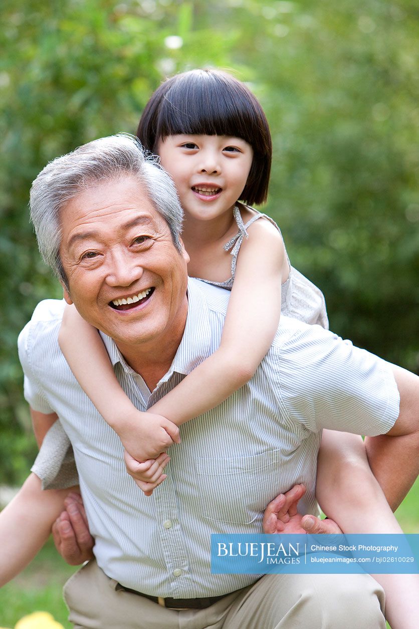Chinese grandpa and grandaughter having fun in garden