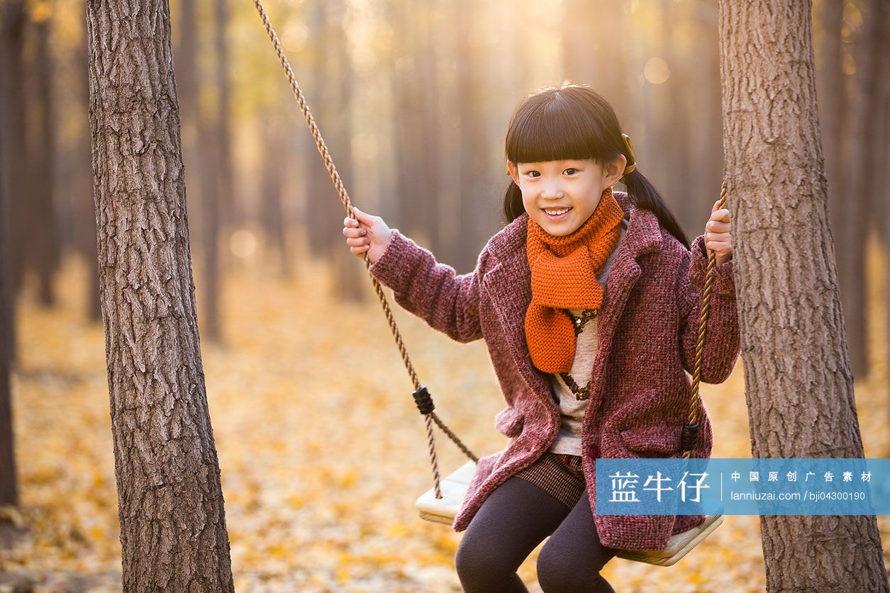 小女孩在秋日树林荡秋千