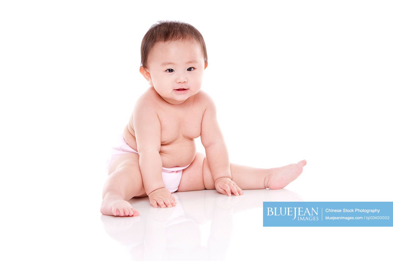 Studio shot of cute Chinese baby sitting on floor