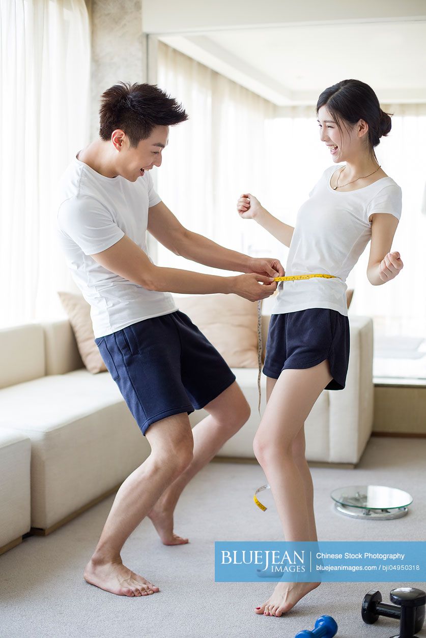 Young Chinese man measuring the waist of his wife