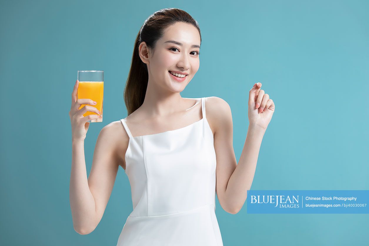 Beautiful young Chinese woman drinking orange juice