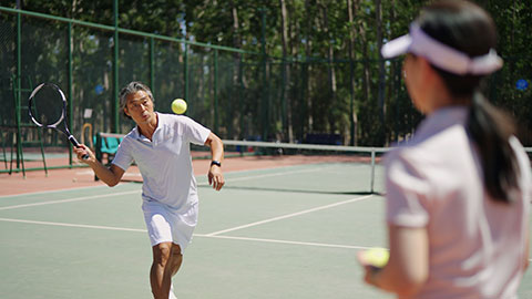 Happy Chinese couple playing tennis ball