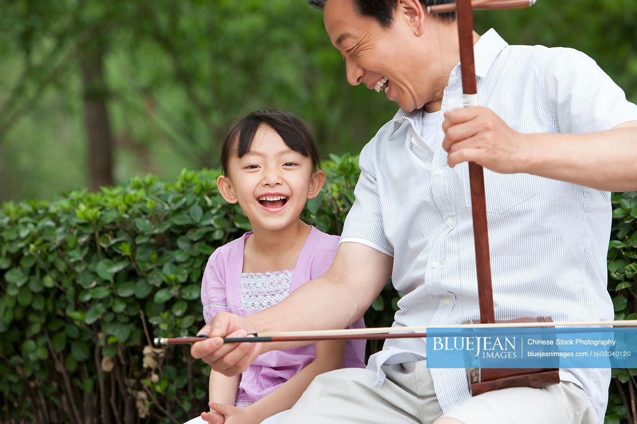 Chinese grandfather playing traditional musical instrument Erhu