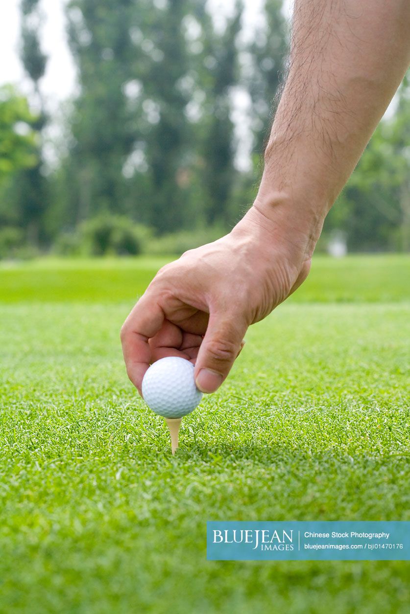 Close-up of putting a golf ball on tee