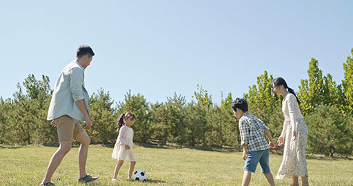快乐的年轻家庭在草地上踢足球