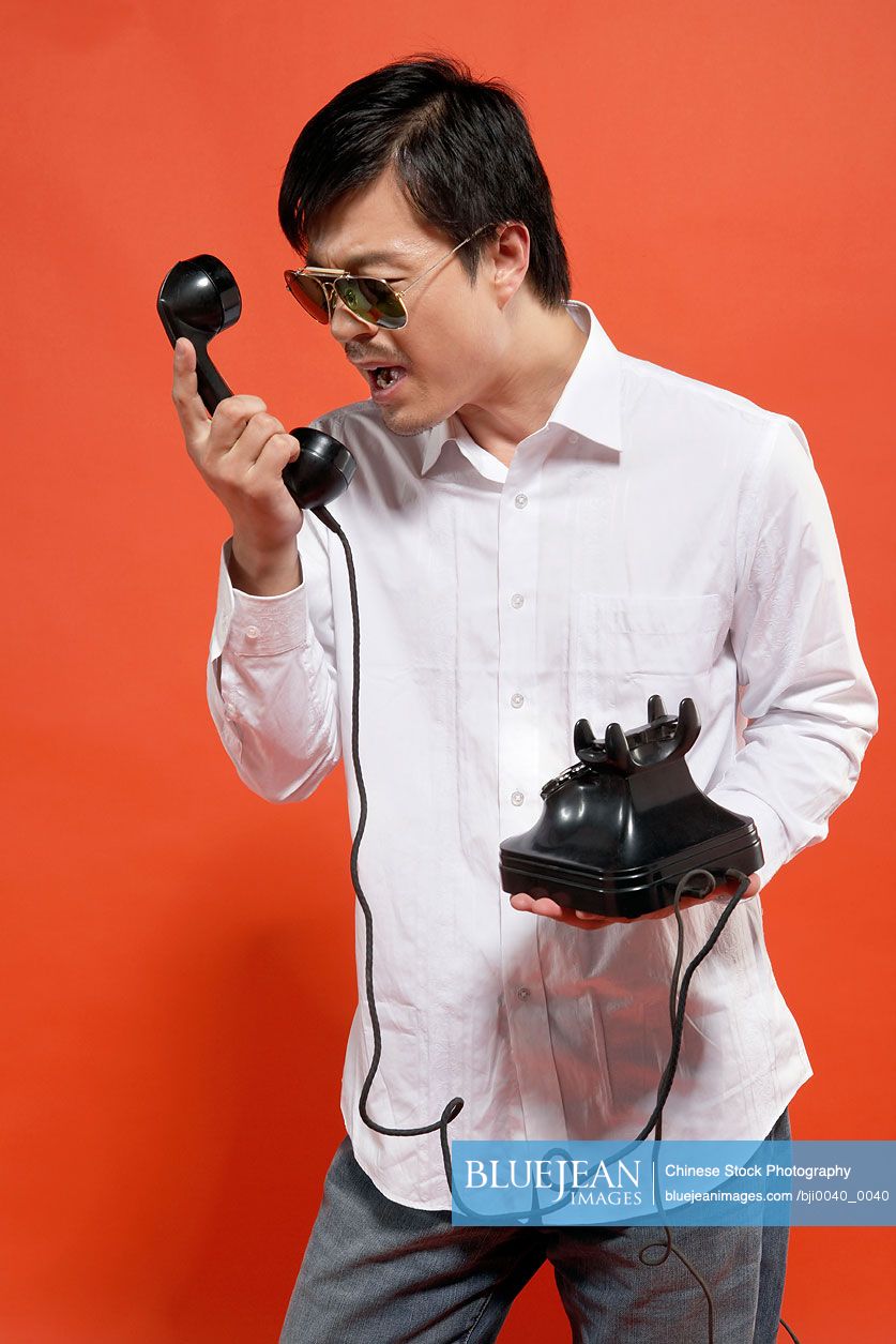 Young Chinese man yelling at telephone