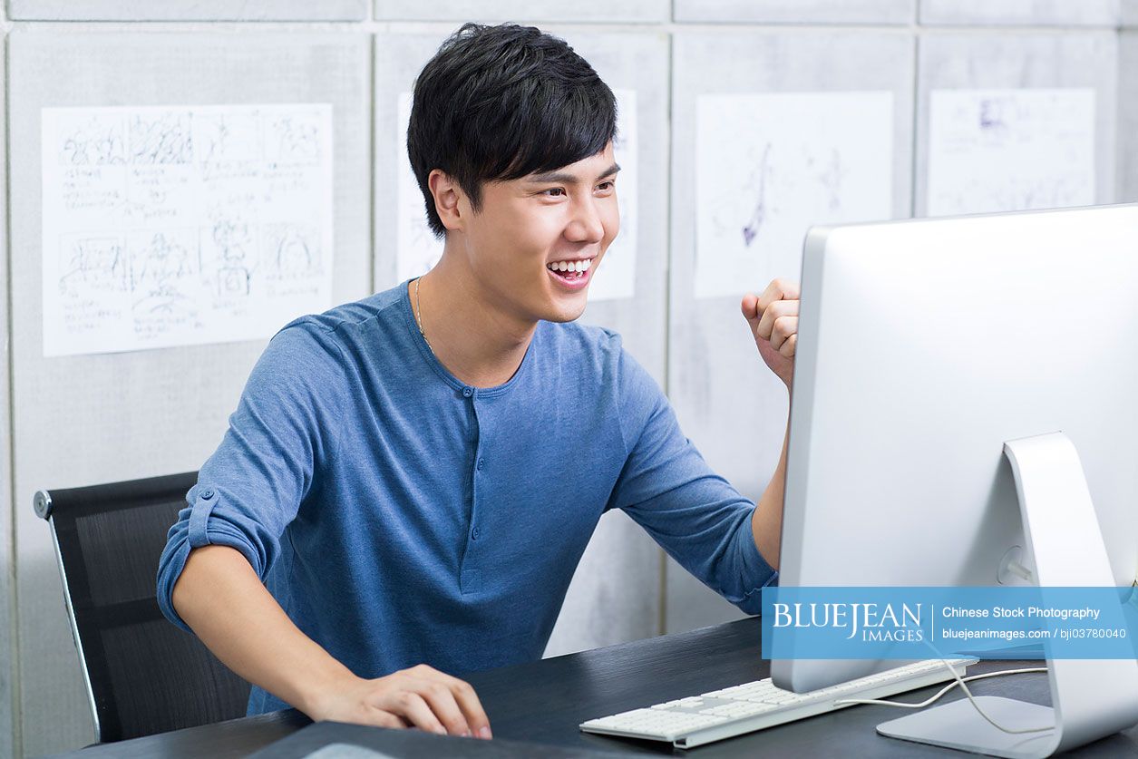 Young Chinese man celebrating in office