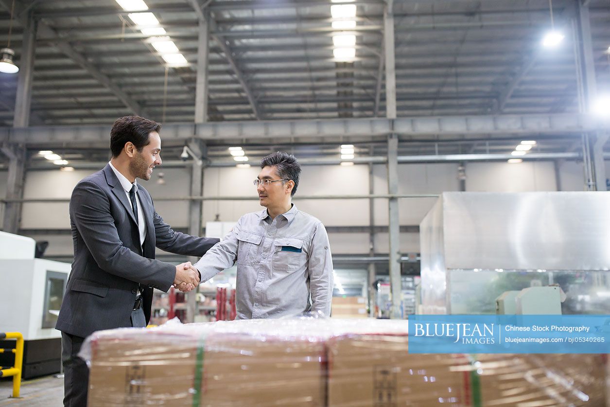 Businessman shaking hands with engineer in the factory