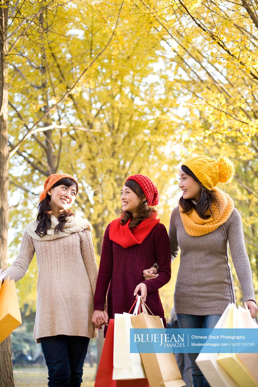 Young Chinese female friends in a park with shopping bags