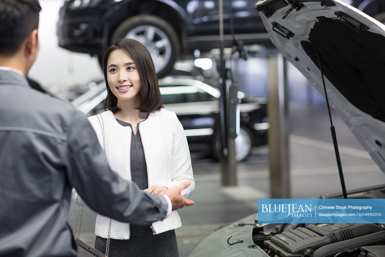 Chinese auto mechanic talking with car owner