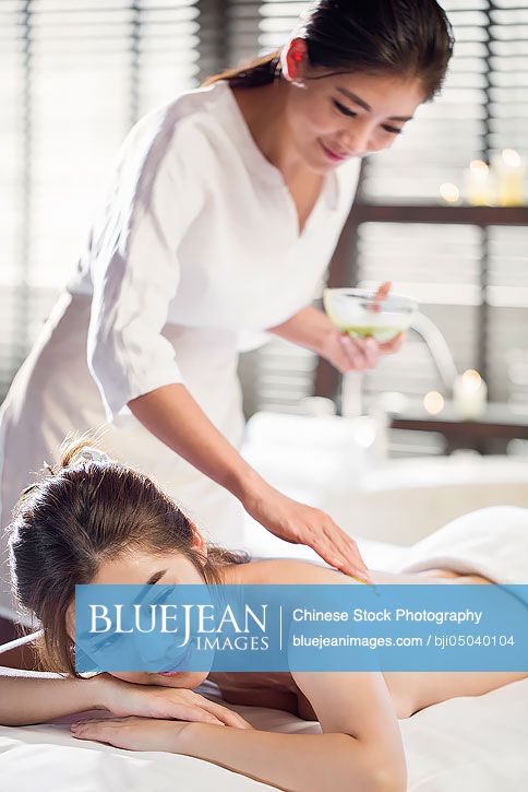 Young Chinese woman receiving back massage at spa center