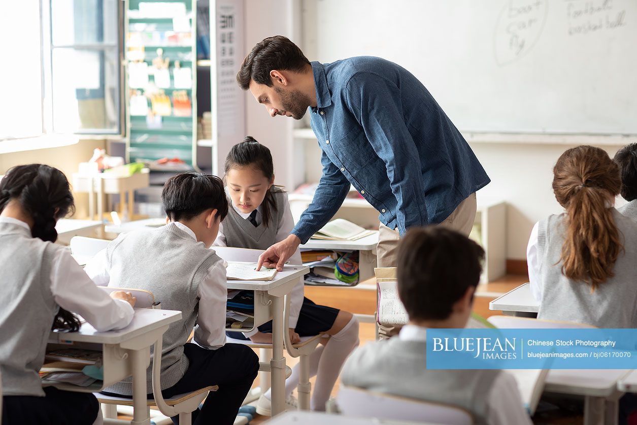 Young teacher helping students in classroom