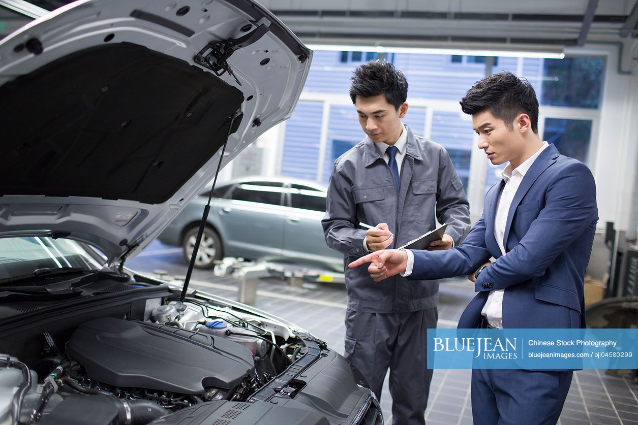 Chinese auto mechanic talking with car owner