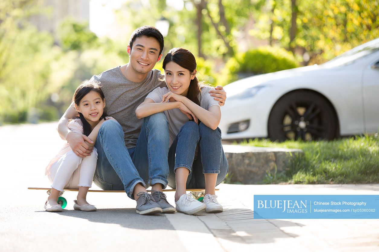 Happy young Chinese family sitting on a skateboard