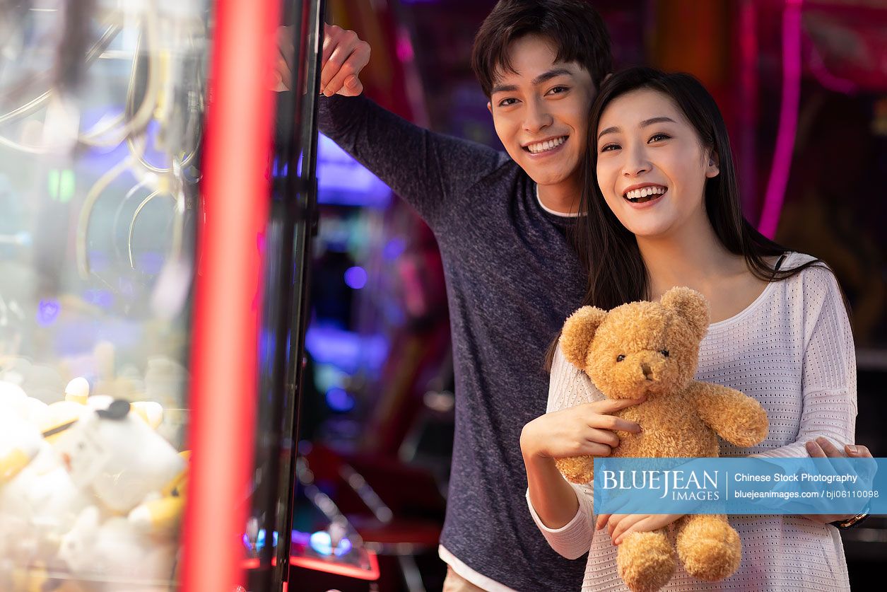 Happy young Chinese couple playing in amusement arcade