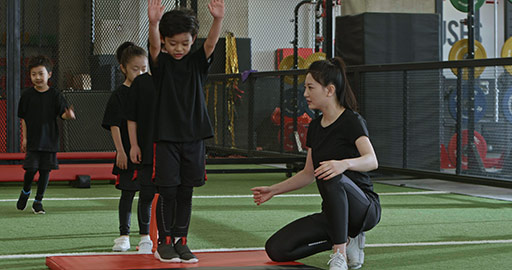Active Chinese children having exercise class with their coach in gym,4K
