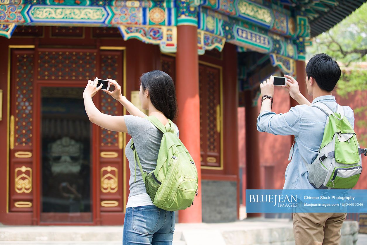 Young Chinese couple taking pictures with smart phones in the Lama Temple