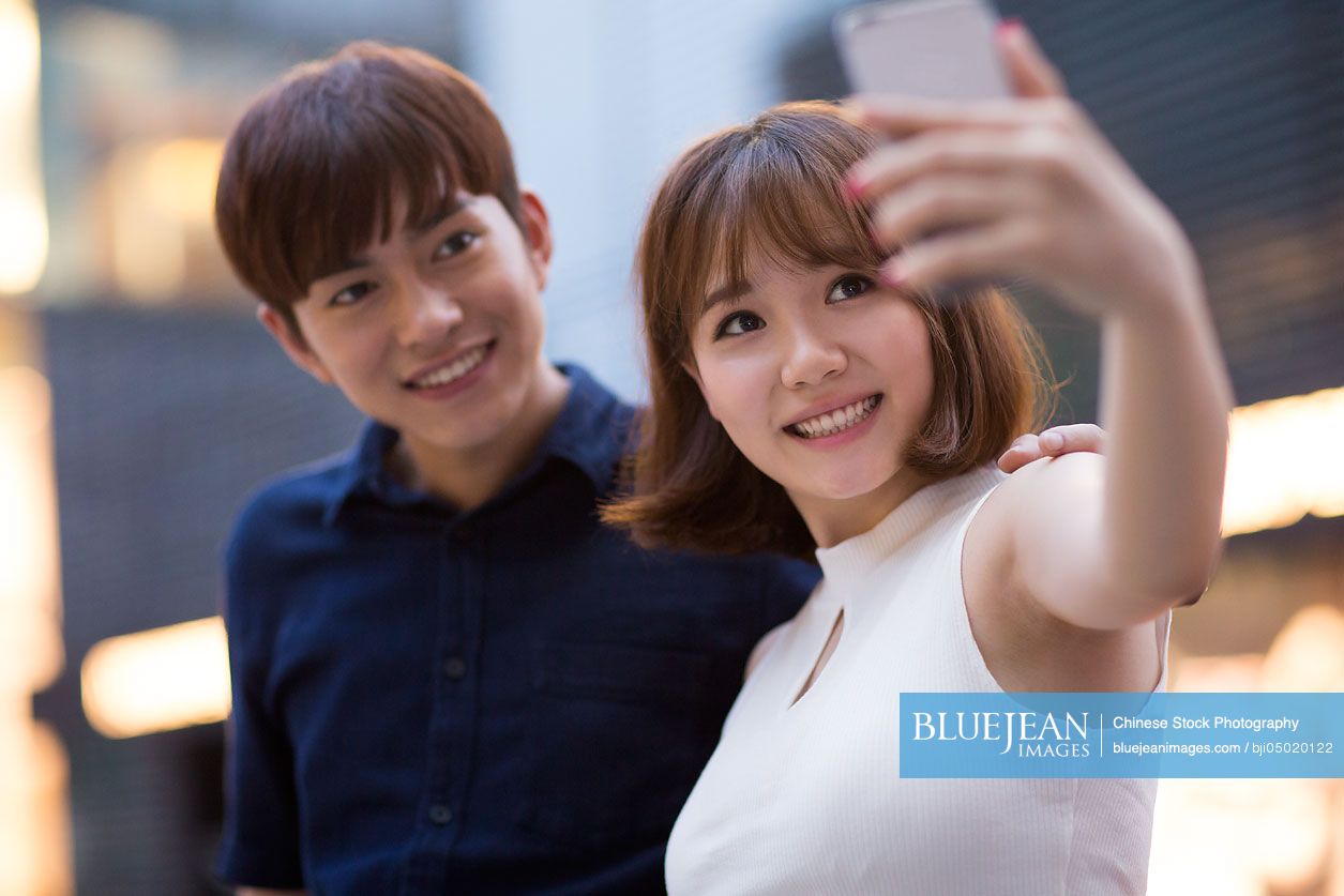 Young Chinese couple taking self portrait with smart phone