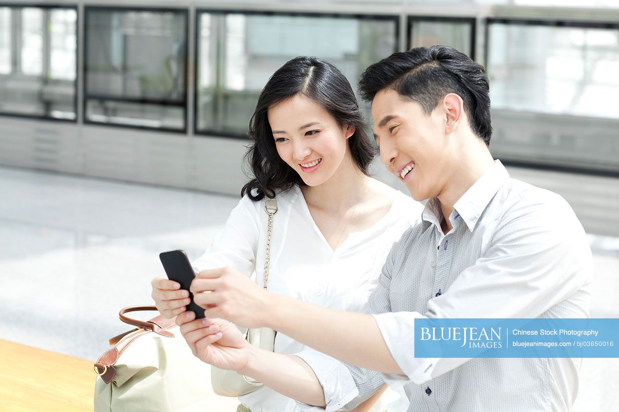 Chinese young couple with mobile phone at subway station