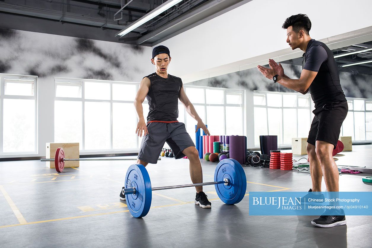 Young Chinese man working with trainer at gym