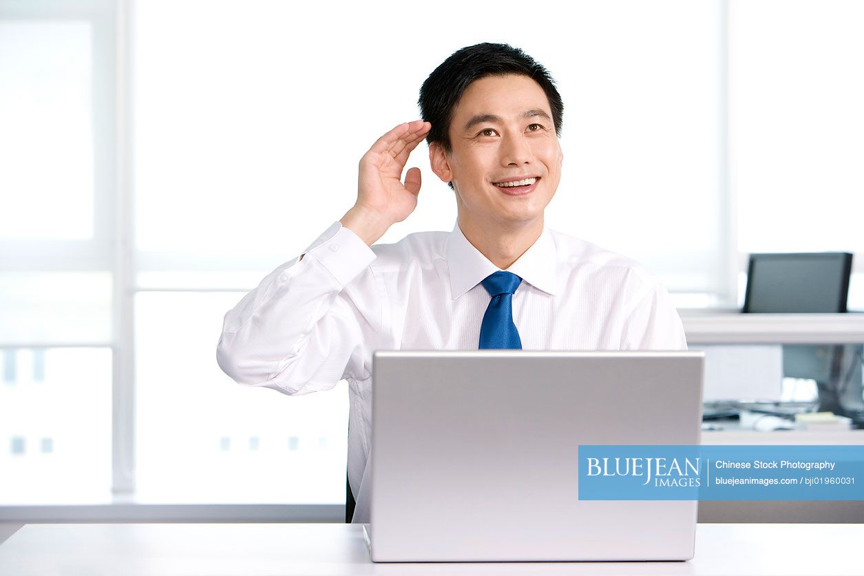Happy Chinese office worker at his desk