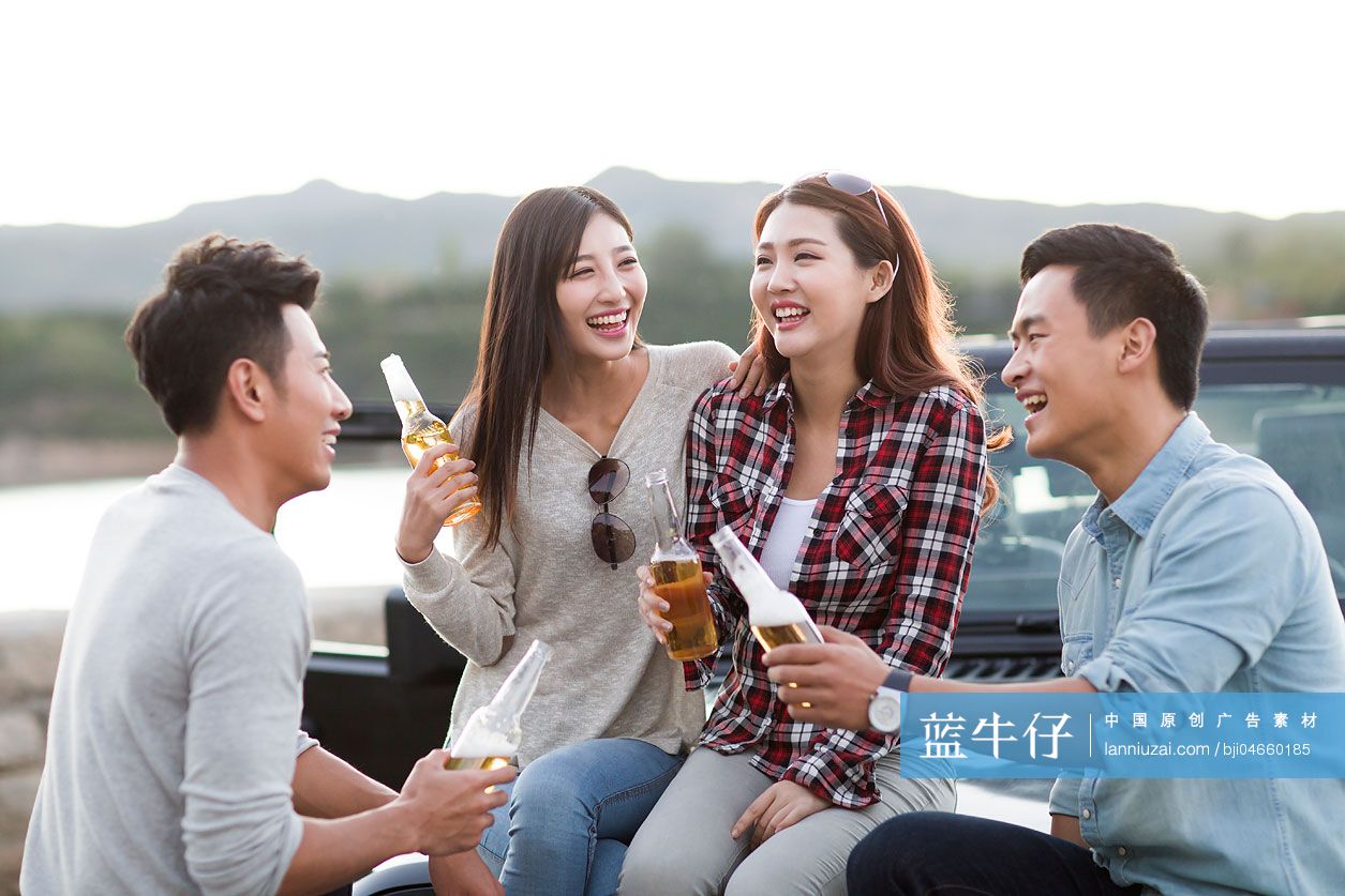 年轻人坐在吉普车上喝啤酒