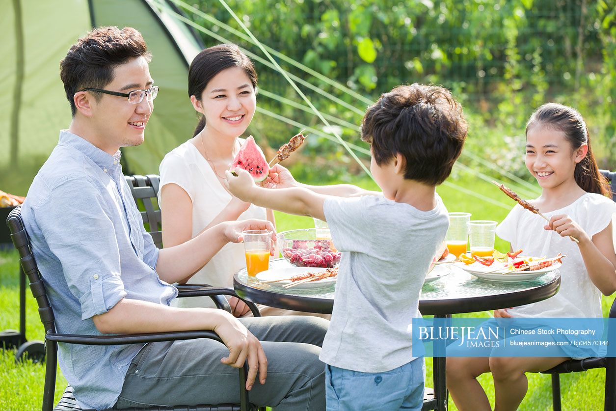 Young Chinese family picnicking outdoors