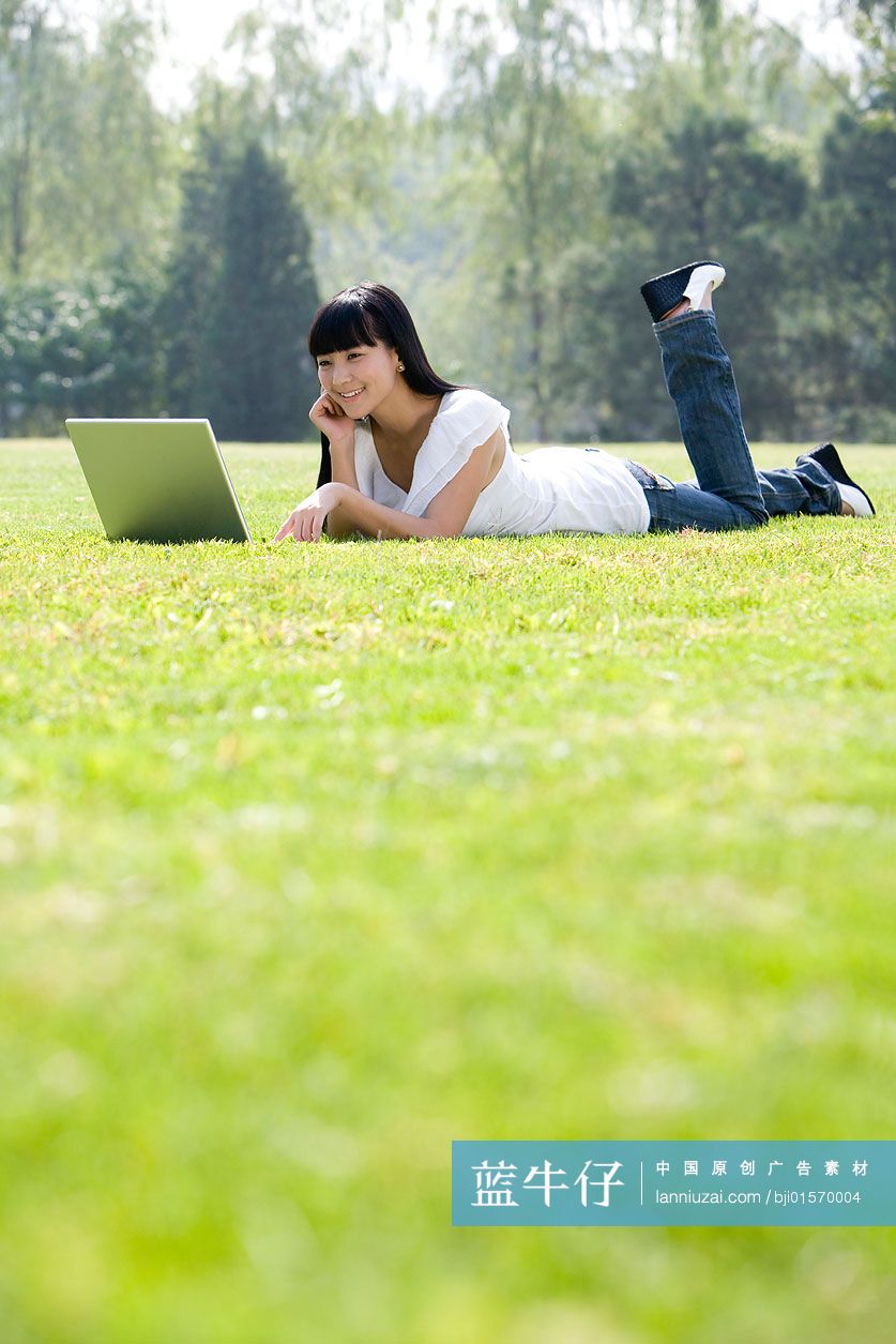 在草地上用电脑的年轻人