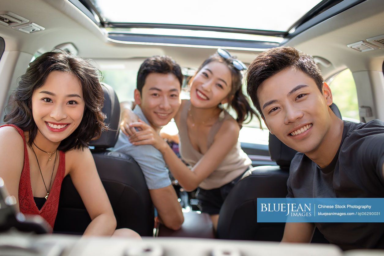 Happy young Chinese friends enjoying road trip